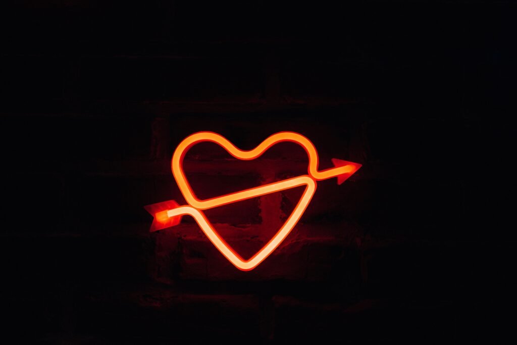 A glowing neon heart with an arrow on a dark background, perfect for romantic themes.